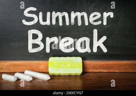 Kreide und Staubwedel auf dem Tisch neben der Tafel mit Inschrift Summer Break. Schulferien Stockfoto