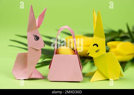 Oster-Origami - zwei Papierhasen und ein Ei mit grünem Hintergrund. Basteln für die Feiertage, machen Sie es selbst. Stockfoto