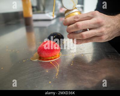 Roter Samt, gesprühter süßer Keks, herzförmig gefüllt mit Karamell und goldenen Pinselstrichen Stockfoto