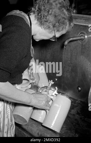 Kellnerin leert Bierkrüge aus dem Münchner Hofbräuhaus am Platzl, 1957. Die Kellnerin leert Bierbecher im Hofbräuhaus am Münchner Platz 1957. Stockfoto