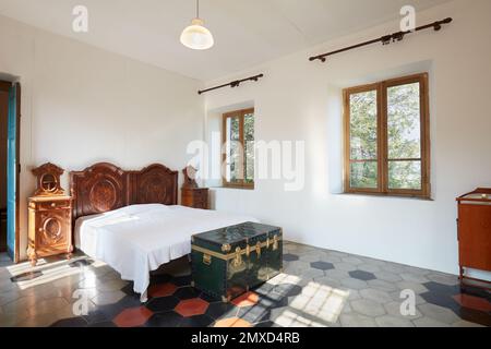 Schlafzimmer im Apartment-Interieur im alten Landhaus an einem sonnigen Tag Stockfoto