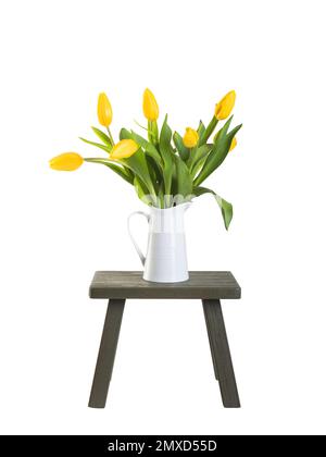 Ein farbenfroher Blumenstrauß aus Tulpen in einer weißen Vase auf einem alten Holzhocker vor einem einfarbigen weißen Hintergrund. Stockfoto