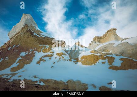 Ein wunderschönes, schneebedecktes Bild von den Hängen des Berges mit Wolken im blauen Himmel im Hintergrund Stockfoto