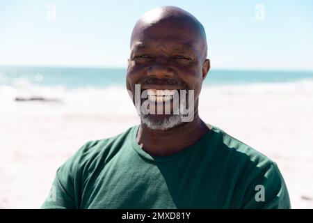 Nahaufnahme eines afroamerikanischen, glatzköpfigen Seniorenmanns, der gegen das Meer lächelt und den klaren Himmel erhellt, Kopierraum Stockfoto