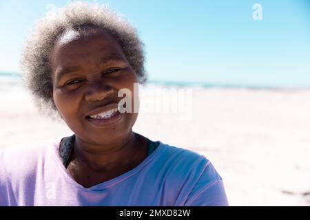 Nahaufnahme eines afroamerikanischen Seniorenmanns mit kurzen grauen Haaren, die am Sandstrand lächeln Stockfoto