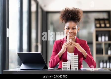 Asiatische Geschäftsfrau, die einen Deal macht, ein Haus oder eine Wohnung im Büro zu kaufen, Hausversicherungs-Konzept Stockfoto