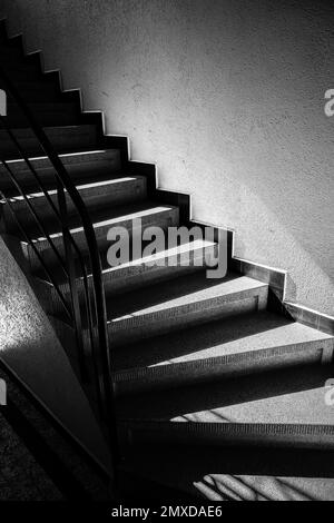 Eine vertikale Graustufenaufnahme von Treppen im Gebäude Stockfoto