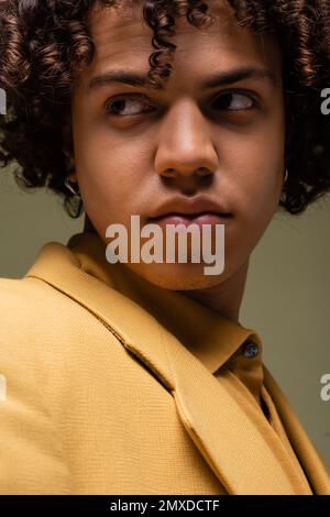 Nahaufnahme eines jungen afroamerikanischen Mannes in gelber Kleidung, der isoliert auf grauem Stockbild wegblickt Stockfoto