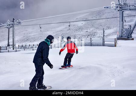 Cairngorm Mountain Aviemore Top Station zwei Snowboarder starten den Hang hinunter oder Rennen Stockfoto