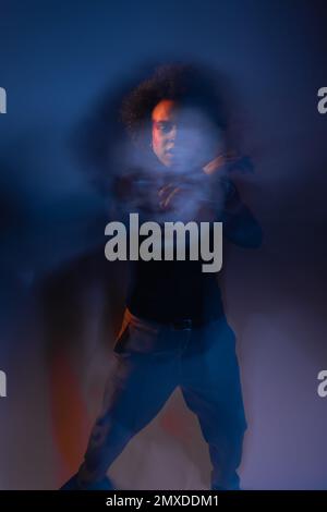 Doppelbelichtung eines misshandelten afroamerikanischen Mannes mit verletztem Gesicht und bipolarer Störung auf dunklem, orangefarbenem und blauem Licht, Stockbild Stockfoto