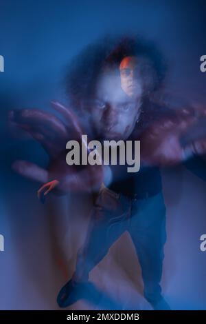 Doppelbelichtung eines verwundeten afroamerikanischen Mannes mit dissoziativer Identitätsstörung, die sich im Dunkeln mit blauem Licht, Stock-Bild bewegt Stockfoto