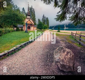 Neblige Morgenszene am Braies Lake mit kleiner Kapelle. Malerischer Herbstblick auf italienische Alpen, Naturpark Fanes-Sennes-Prags, Italien, Europa. Auf Reisen Stockfoto