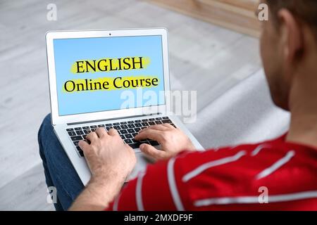 Junger Mann, der sein Notebook für das Online-Englischlernen zu Hause benutzt, Nahaufnahme Stockfoto