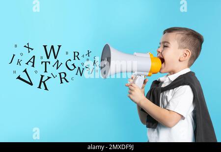 Süßer lustiger Junge mit Megafon und Buchstaben auf hellblauem Hintergrund. Sprachtherapiekonzept Stockfoto