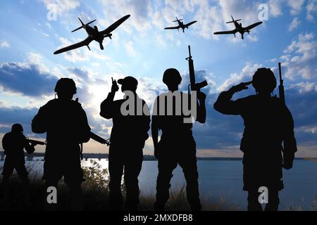 Silhouetten von Soldaten in Uniform mit Sturmgewehren und Militärflugzeugen, die draußen patrouillieren Stockfoto
