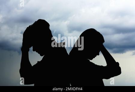 Silhouetten eines streitenden Paares gegen den Himmel mit schweren Regenwolken. Beziehungsprobleme Stockfoto