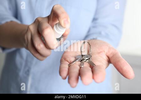 Frau, die Antiseptikum auf Schlüssel spritzt, Nahaufnahme Stockfoto