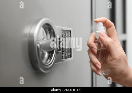 Frau, die Antiseptikum auf die Tastatur des modernen Safes sprüht, Nahaufnahme Stockfoto