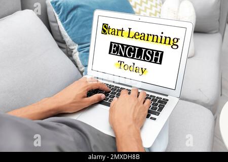 Mann, der zu Hause ein Notebook zum Online-Englischlernen verwendet Stockfoto