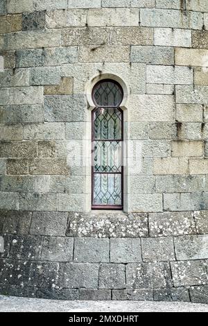 Das alte mittelalterliche Fenster, umgeben von einer Steinmauer, zieht die Aufmerksamkeit der Touristen auf sich. Historische Fassade mit hellem Sonnenlicht Stockfoto