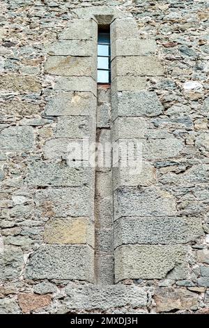 Das alte mittelalterliche Fenster, umgeben von einer Steinmauer, zieht die Aufmerksamkeit der Touristen auf sich. Historische Fassade mit hellem Sonnenlicht Stockfoto