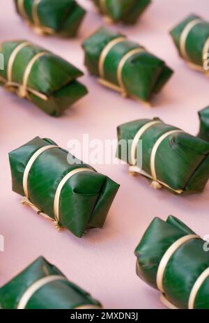 Top View thailändische Tradition süßes Dessert hergestellt mit Bohnen Kokosmilch klebriger Reis Umhang mit frischem Bananenblatt Natur grün niedliches Paket Bambusbündel auf Nadel Stockfoto
