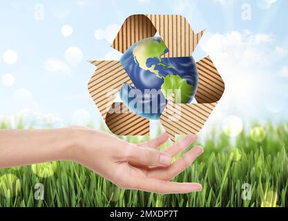 Eine Frau mit einer Darstellung der Erde und des Recycling-Symbols in der Hand, Nahaufnahme Stockfoto