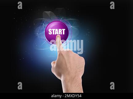 Mann zeigt auf das Startsymbol auf dunklem Hintergrund, Nahaufnahme Stockfoto