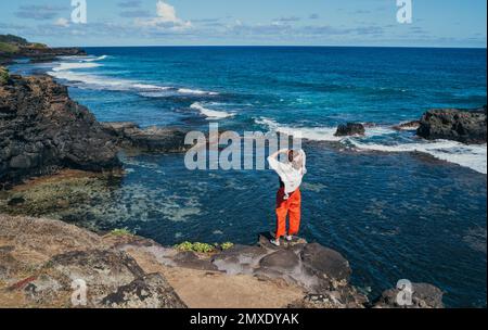 Einsame Frau kleidete leichte Sommerkleidung und genoss den Blick auf den Indischen Ozean mit starker Brandung auf den Klippen am Gris Gris Aussichtspunkt, extrem südlich der Insel Mauritius Stockfoto