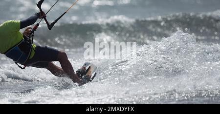 Sportlicher Mann springen auf Kite Surfbrett auf den Wellen des Meeres Stockfoto