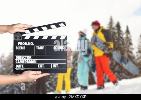 Assistent hält Klapperbrett und Leute auf schneebedeckten Hängen, Nahaufnahme. Kinoproduktion Stockfoto