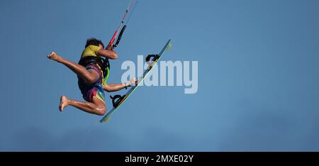 Ein sportlicher Mann springt auf einem Kitesurf-Brett auf einer Meereswelle, Kiteboarding Actionfotos Stockfoto