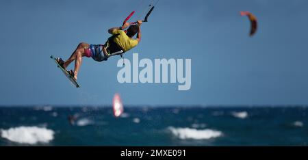 Ein sportlicher Mann springt auf einem Kitesurf-Brett auf einer Meereswelle, Kiteboarding Actionfotos Stockfoto