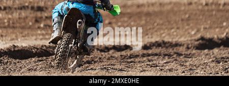 Rennfahrer-Kind auf dem Motorrad nimmt am Motocross-Rennen Teil, am aktiven Extremsport Stockfoto