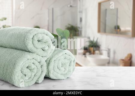 Frische Handtücher und Eukalyptuszweig auf Marmortisch im Badezimmer. Platz für Text Stockfoto