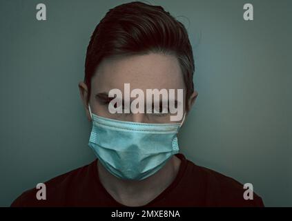 Eine schöne Aufnahme eines jungen weißhäutigen Models, das eine Maske trägt und in die Kamera schaut Stockfoto
