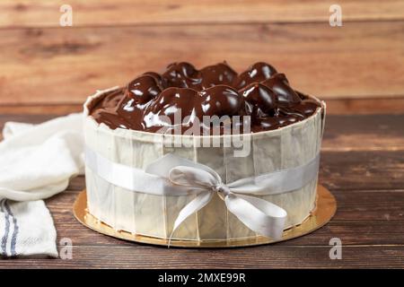 Profiterole-Kuchen. Kuchen mit Profiteroles, umgeben von weißer Schokolade auf Holzhintergrund. Schließen Stockfoto