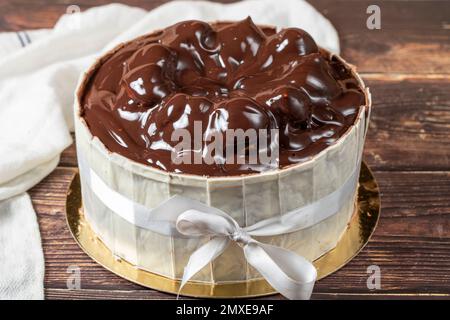 Profiterole-Kuchen. Kuchen mit Profiteroles, umgeben von weißer Schokolade auf Holzhintergrund. Schließen Stockfoto