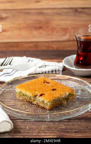 Türkische Pistazien-Kadayif. Türkische Köstlichkeiten. Kadayif-Dessert auf einem Teller mit Holzhintergrund. Schließen Stockfoto