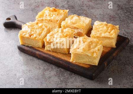 Griechischer Puddingkuchen Galaktoboureko mit Grieß-Creme-Naht auf dem Holzbrett auf dem Tisch. Horizontal Stockfoto