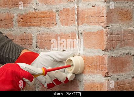 Installation von Steckdosen im Retro-Stil an einer Ziegelwand Stockfoto