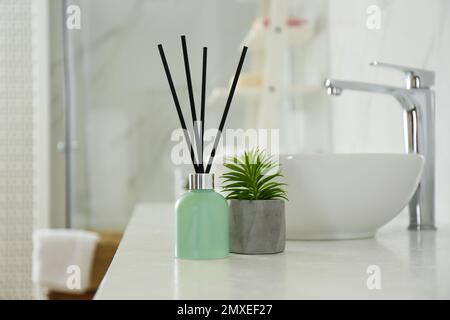 Reed-Lufterfrischer und Zimmerpflanzen auf der Theke im Badezimmer Stockfoto