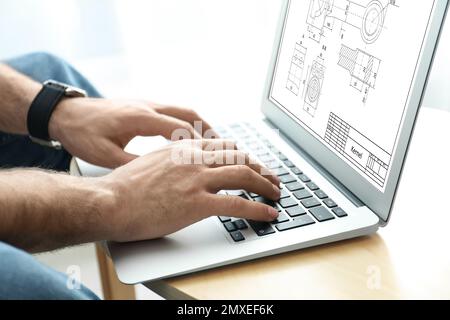 Männlicher Ingenieur, der mit technischem Zeichnen auf einem Laptop am Tisch arbeitet, Nahaufnahme Stockfoto