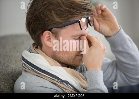 Junger Geschäftsmann, der die Brille abnimmt, fühlt sich anstrengend an den Augen Stockfoto