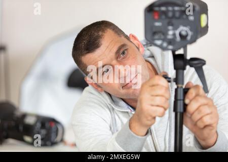 Der Fotograf passt die Höhe des Studiostrahls an Stockfoto