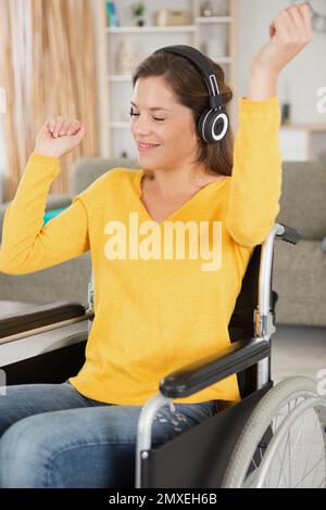 Eine Frau im Rollstuhl, die Kopfhörer trägt und zur Musik tanzt Stockfoto