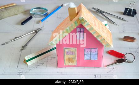 Bau- und Architekturkonzept. Fiktive Zeichnung und Plan eines Wohngebäudes süßes Modellhaus und verschiedene Werkzeuge Stockfoto