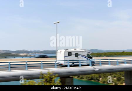 Eine verschwommene Bewegung von Verkehrsbarrieren und ein weißer Van, der auf der Autobahn fährt Stockfoto