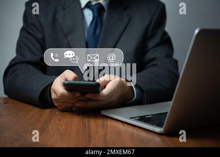 Geschäftsmann, der ein Smartphone verwendet, um Kontakt aufzunehmen Information.Geschäftskonzept der Kontaktaufnahme per E-Mail mit grafischem Symbol. Stockfoto