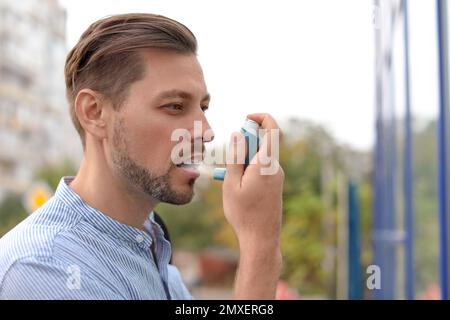 Mann, der Asthma-Inhalator im Freien verwendet. Gesundheitswesen Stockfoto